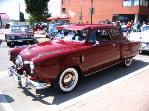 1993 Ford Taurus - A classic maroon sedan with distinctive chrome trim is displayed at an outdoor car show.