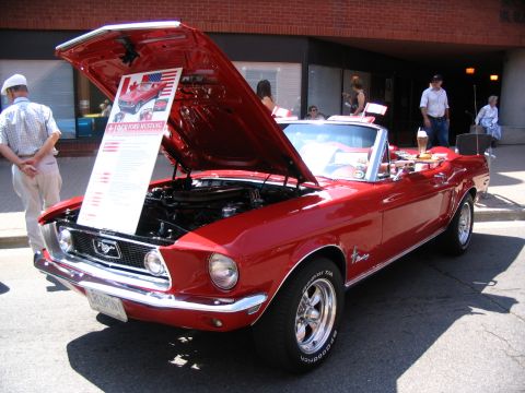 1993 Ford Taurus - A red 1969 Ford Mustang convertible is displayed with its hood open, revealing an information board.
