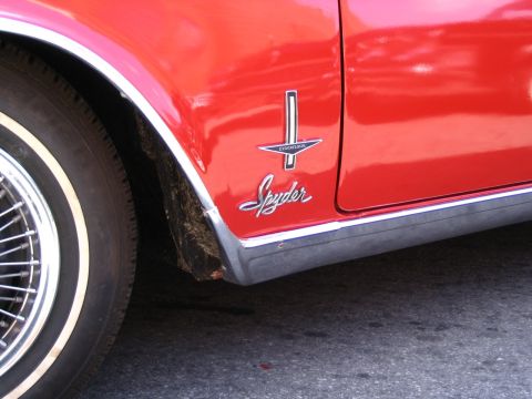 1993 Ford Taurus - A close-up view of a red car's fender shows a 'Spyder' emblem and chrome trim.