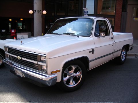 1993 Ford Taurus - This white pickup truck, likely from the 1980s, is parked on a city street.
