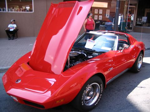 1993 Ford Taurus - Red 1975 Chevrolet Corvette Stingray on display at a car show, hood open to reveal the engine.