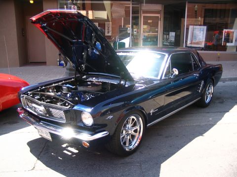 1993 Ford Taurus - A classic dark blue Ford Mustang is displayed with its hood open, parked on a street.