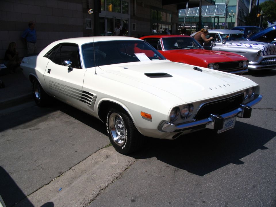 White 1970s Dodge Challenger parked on street, other cars behind it