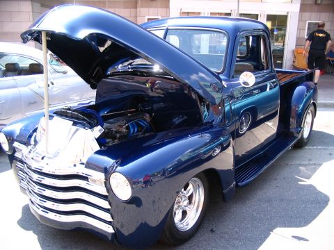 1993 Ford Taurus - A classic blue pickup truck from the 1950s is displayed with its hood open at a car show.