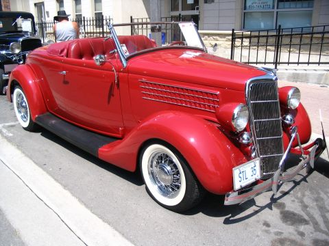1993 Ford Taurus - Classic red convertible with wire wheels and whitewall tires on display at a car show.