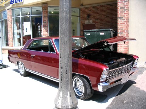 1993 Ford Taurus - A maroon coupe is parked in front of a brick building with its hood open, revealing the engine.