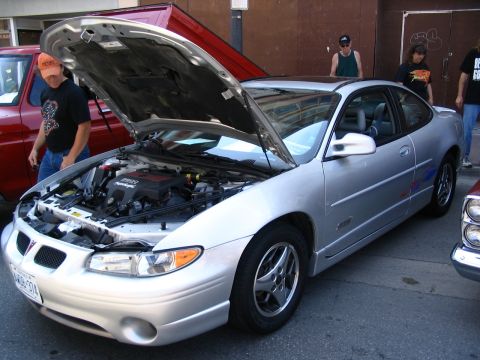 1993 Ford Taurus - A silver Pontiac Grand Prix coupe is displayed with its hood open at a car show, revealing the engine compartment.