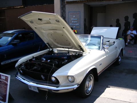 1993 Ford Taurus - A white 1969 Ford Mustang convertible is displayed with its hood open, next to a blue Ford Mustang.
