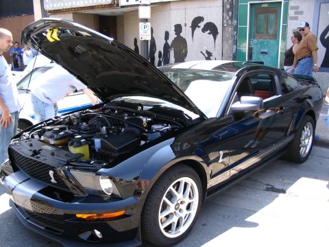 1993 Ford Taurus - A black 2007 Ford Mustang Shelby GT500 is displayed with its hood open, revealing the engine bay.