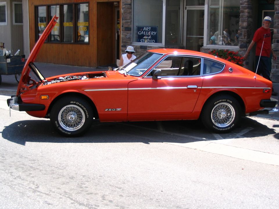 Orange 1977 Datsun 280Z with hood open, parked on street