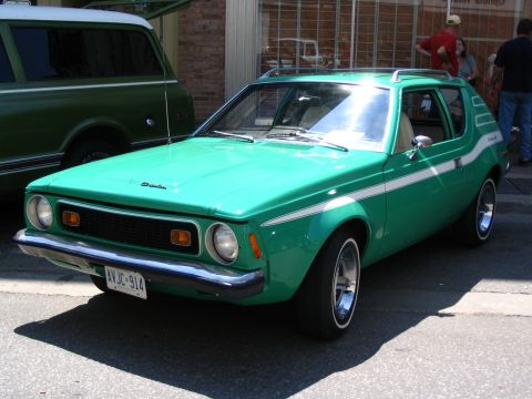 1993 Ford Taurus - A green AMC Gremlin is parked on a street, with a large green SUV to its left.