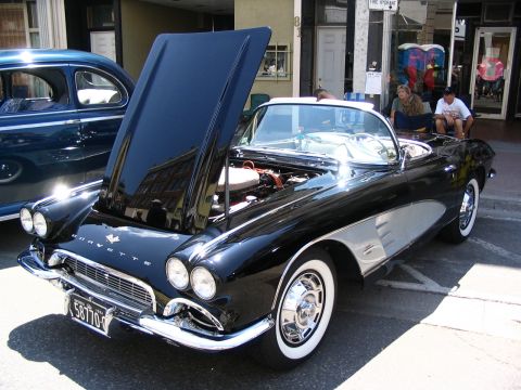 1993 Ford Taurus - A black 1958 Corvette convertible is displayed with its hood open at a car show, revealing the engine and chrome details.