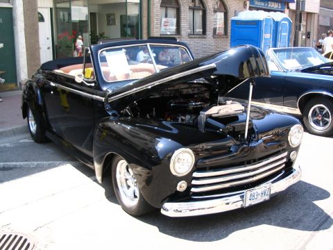 1993 Ford Taurus - Black 1946 Ford convertible on display at a car show, hood raised to reveal the engine.