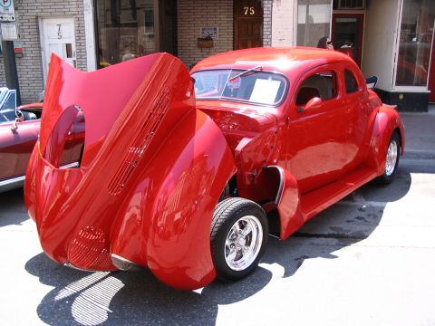 1993 Ford Taurus - A bright red coupe is displayed with its hood open at a car show, revealing the engine compartment.