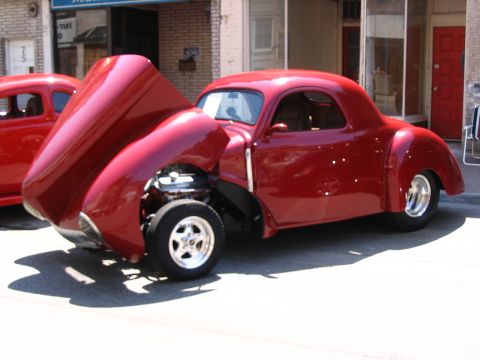 1993 Ford Taurus - A custom red coupe hot rod is displayed with its hood open, revealing the engine compartment.