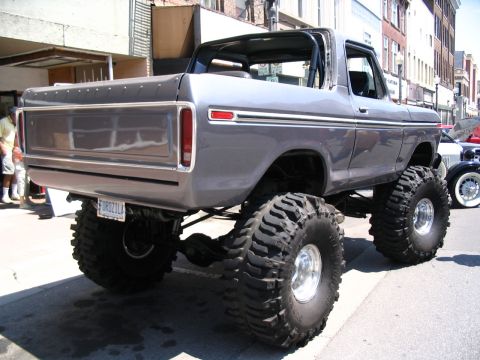 1993 Ford Taurus - A heavily modified pickup truck with oversized tires is parked on a city street.