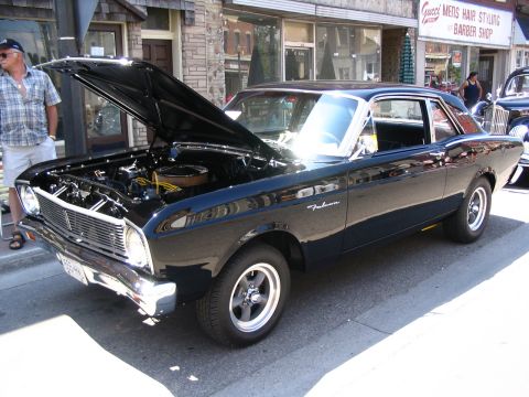 1993 Ford Taurus - Black 1966 Ford Falcon coupe displayed at a car show with its hood open.