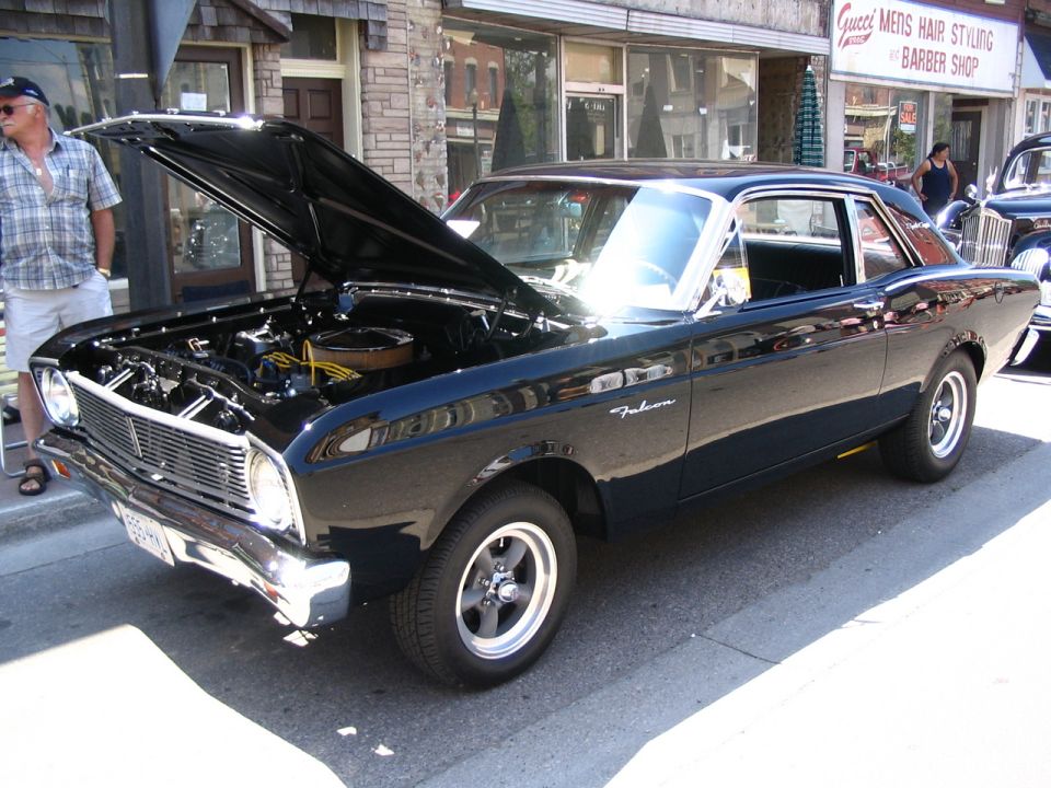Black 1966 Ford Falcon coupe, hood open showing engine. Chrome grille and bumper