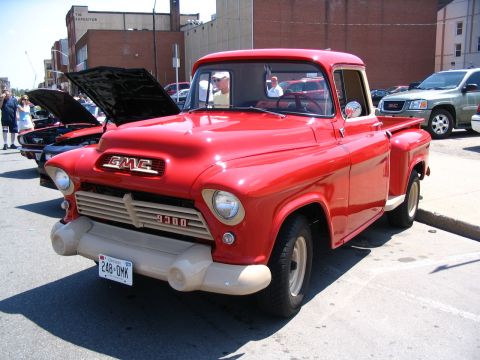 1993 Ford Taurus - A classic red GMC pickup truck is displayed at an outdoor car show.