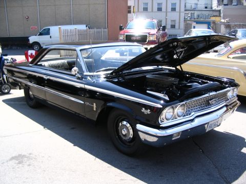 1993 Ford Taurus - A classic black Ford Galaxie is displayed with its hood open, parked outdoors next to another vintage vehicle.