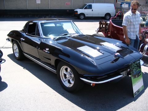 1993 Ford Taurus - A black 1965 Chevrolet Corvette coupe is displayed at a car show, its distinctive body style and chrome accents.
