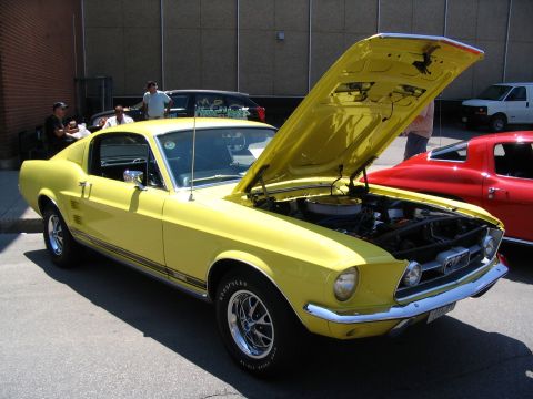 1993 Ford Taurus - A yellow 1967 Ford Mustang fastback is displayed with its hood open, revealing the engine compartment.