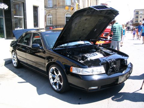 1993 Ford Taurus - Black sedan on display with hood and trunk open at an outdoor car show.
