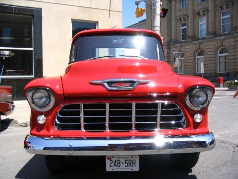 1993 Ford Taurus - A bright red 1955 Chevrolet truck is shown from the front, its iconic chrome grille and bumper.