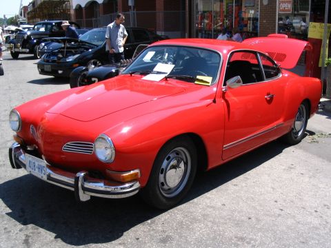 1993 Ford Taurus - A red Volkswagen Karmann Ghia is displayed at an outdoor car show with other vehicles in the background.
