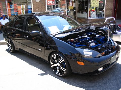 1993 Ford Taurus - Customized black sedan with aftermarket wheels and engine modifications on display.