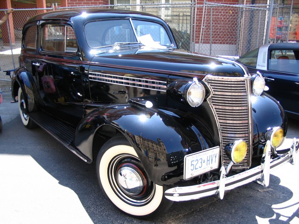 Black sedan with whitewall tires and a chrome grille, parked outdoors