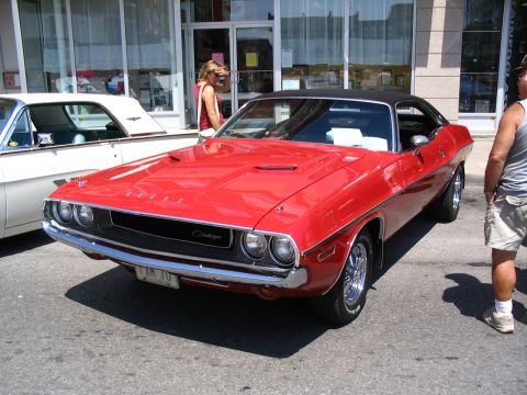 1993 Ford Taurus - A classic red Dodge Challenger is parked on the street, with another vehicle beside it and a building in the background.