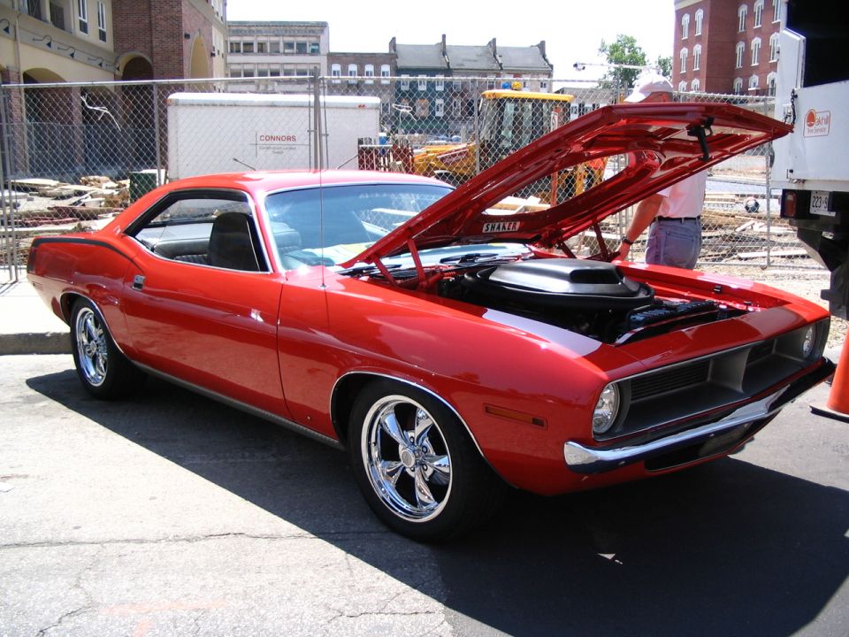 Red muscle car with hood open, chrome wheels, and a shaker hood scoop