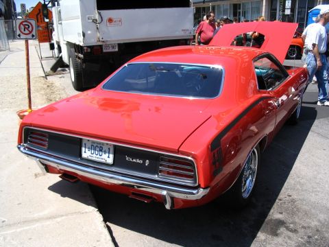1993 Ford Taurus - A red muscle car, possibly a 1970 Plymouth Barracuda, is seen from the rear at a car show.