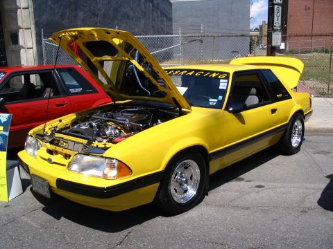 1993 Ford Taurus - Yellow coupe with hood and trunk open, displaying its engine bay at a car show.