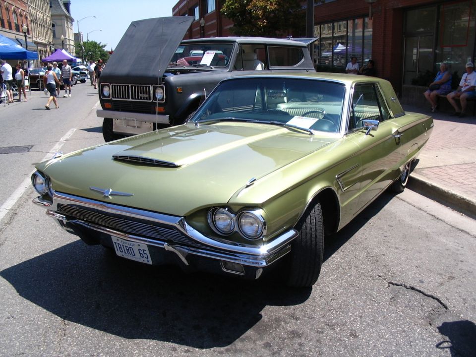 Green 1965 Ford Thunderbird with a black International Harvester Scout behind it