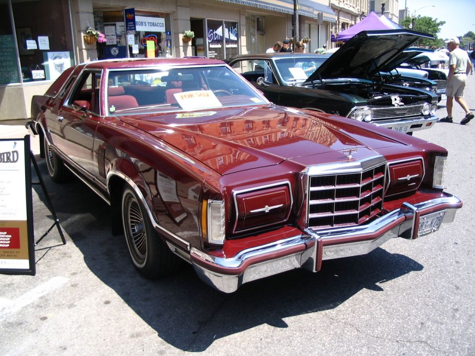 Maroon coupe front 3/4 view with chrome grille and prominent headlights