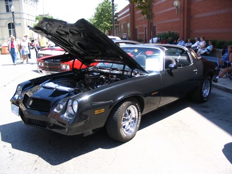 1993 Ford Taurus - Black 1978 Chevrolet Camaro Z28 displayed at a car show with its hood open.
