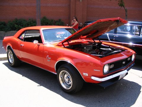 1993 Ford Taurus - Classic red 1967 Camaro SS with its hood open, parked next to another vehicle.