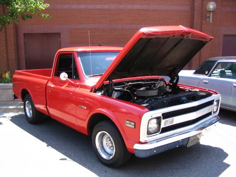 1993 Ford Taurus - A red pickup truck is parked with its hood open, revealing the engine compartment. Another vehicle is visible to the right.