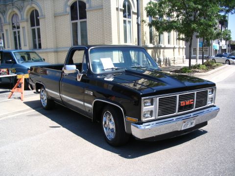 1993 Ford Taurus - A black GMC pickup truck is parked on a street next to a blue pickup truck.
