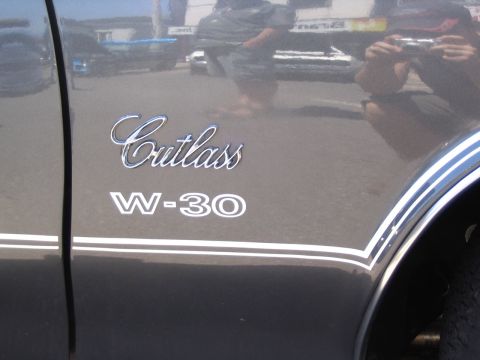 1993 Ford Taurus - Close-up of the "Cutlass W-30" emblem and racing stripes on the side of a car.