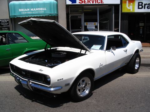 1993 Ford Taurus - A white 1967 Chevrolet Camaro SS is displayed with its hood up, revealing the engine bay.