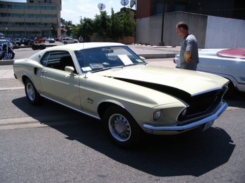 1993 Ford Taurus - A 1969 Ford Mustang Mach 1 is displayed with its hood open at an outdoor car show.