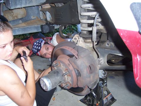 1991 Ford Bronco - Two individuals are shown performing maintenance on the brake and suspension components of a vehicle.