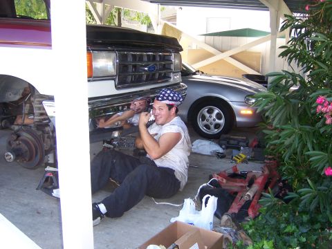 1991 Ford Bronco - A man wearing an American flag bandana works on the underside of a 1991 Ford Bronco.