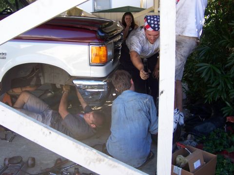 1991 Ford Bronco - Several people are gathered around a truck, appearing to be working on its undercarriage.