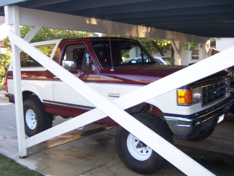 1991 Ford Bronco - This two-tone 1991 Ford Bronco is parked under a carport, showing its front three-quarter view.