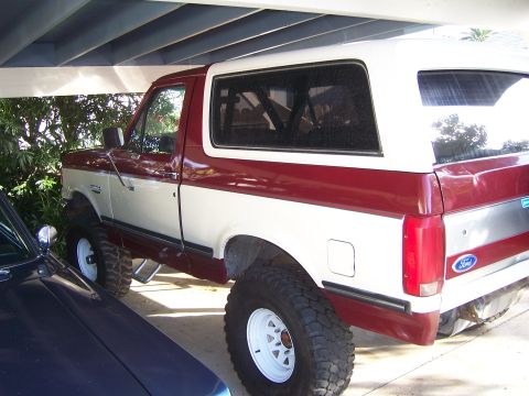1991 Ford Bronco - Lifted 1991 Ford Bronco in two-tone red and white, parked under a carport.