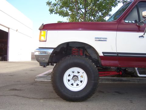 1991 Ford Bronco - Close-up of a lifted Ford Bronco's front wheel and suspension system, showing off its off-road capabilities.